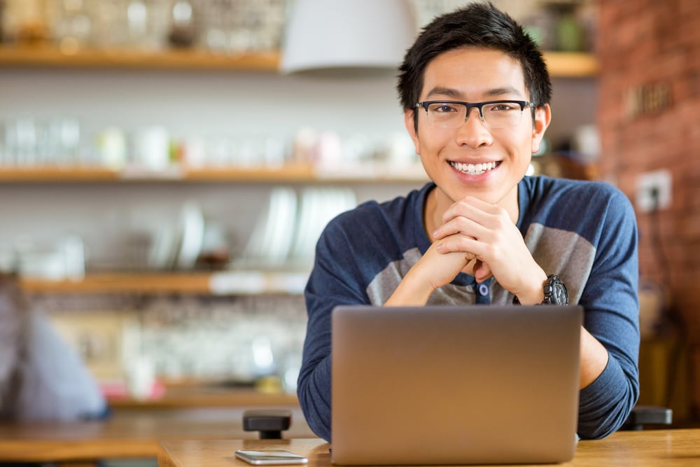 Portrait of positive asian male in glasses with laptop in cafe Portrait of positive asian male in glasses with laptop in cafe
