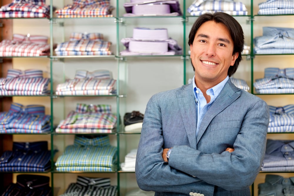 Smiling shop manager in front of tshirts